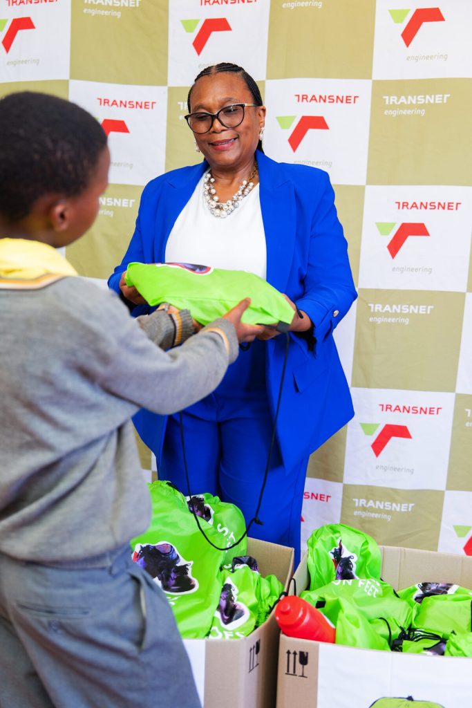 Pictured is the school's principal Thembeka Hini handing over school shoes to a learner.