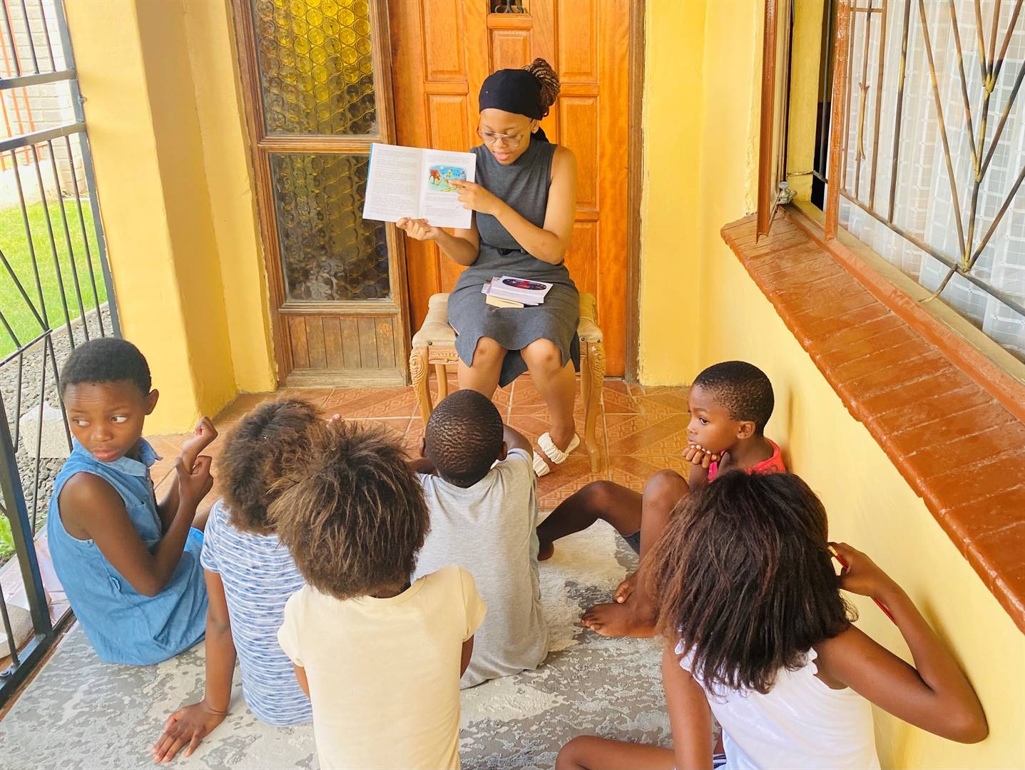 Basetsana Sheane is seen here reading aloud the story Mosadimoholo Le Kolobe Ya Hae to some children.