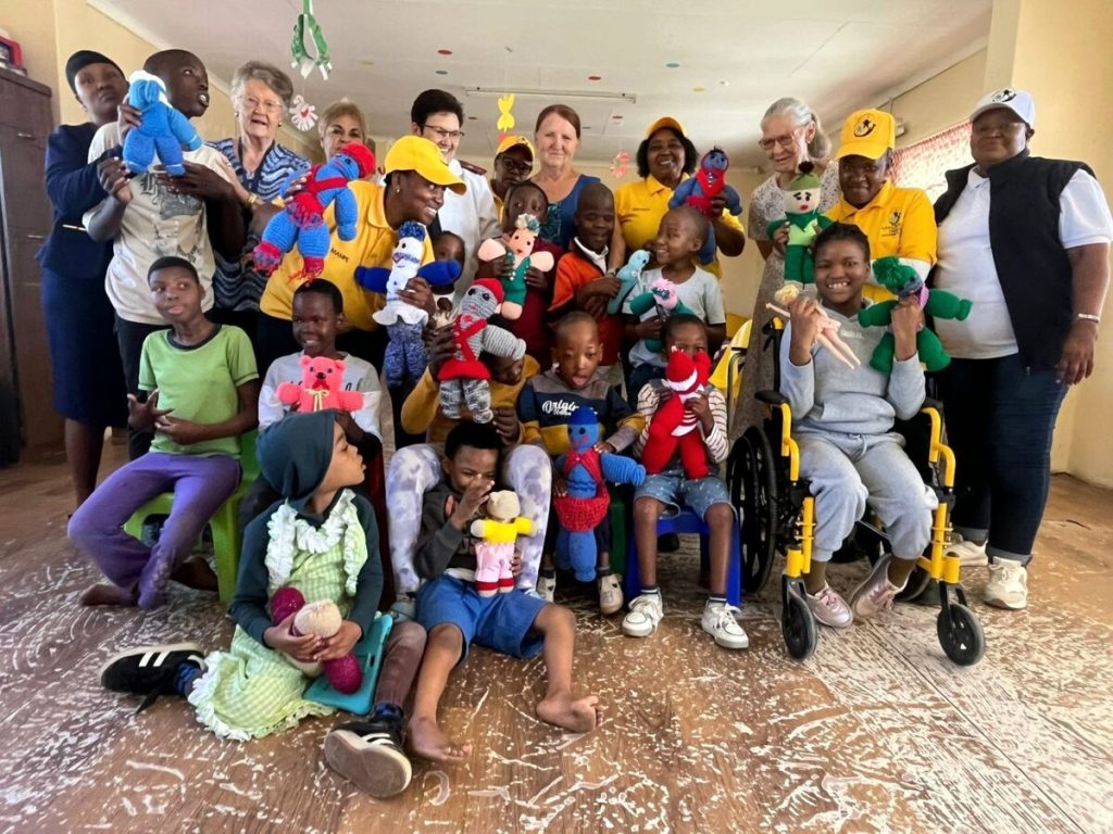 Met die kinders van die sentrum wat poppe ontvang het is verteenwoordigers van die projek en sentrum.