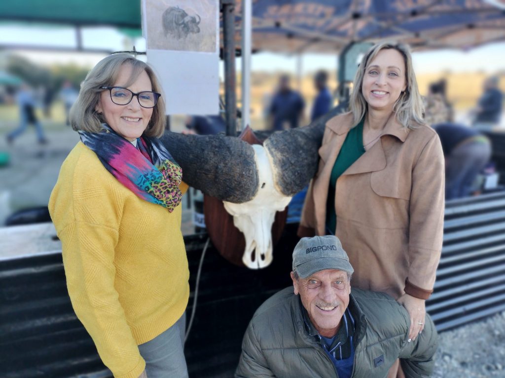 Hannelie Henning en haar man, Charl (voor) van Pretoria en hul dogter Carla Barnard (van Catu) het poseer by die buffelkop by die stalletjie waar 'n buffel vanjaar vir die eerste keer op die WildsKOSfees op 'n spit gaargemaak is.