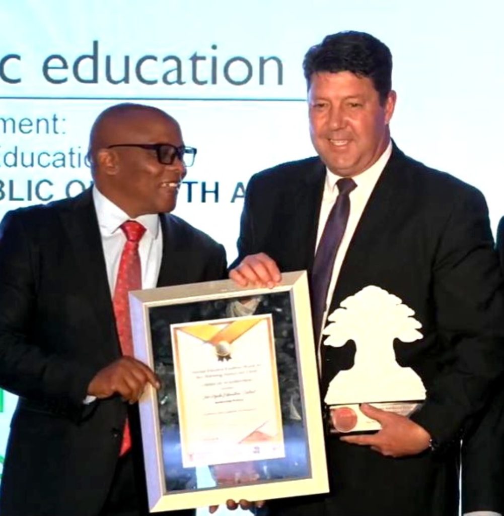 Dr. Vusimzi Chuta, distrikdirekteur van die Fezile Dabi onderwysdistrik, oorhandig die eerbewys Jaco Viljoen, skoolhoof van Laerskool Trio  in Kroonstad. Foto:Verskaf