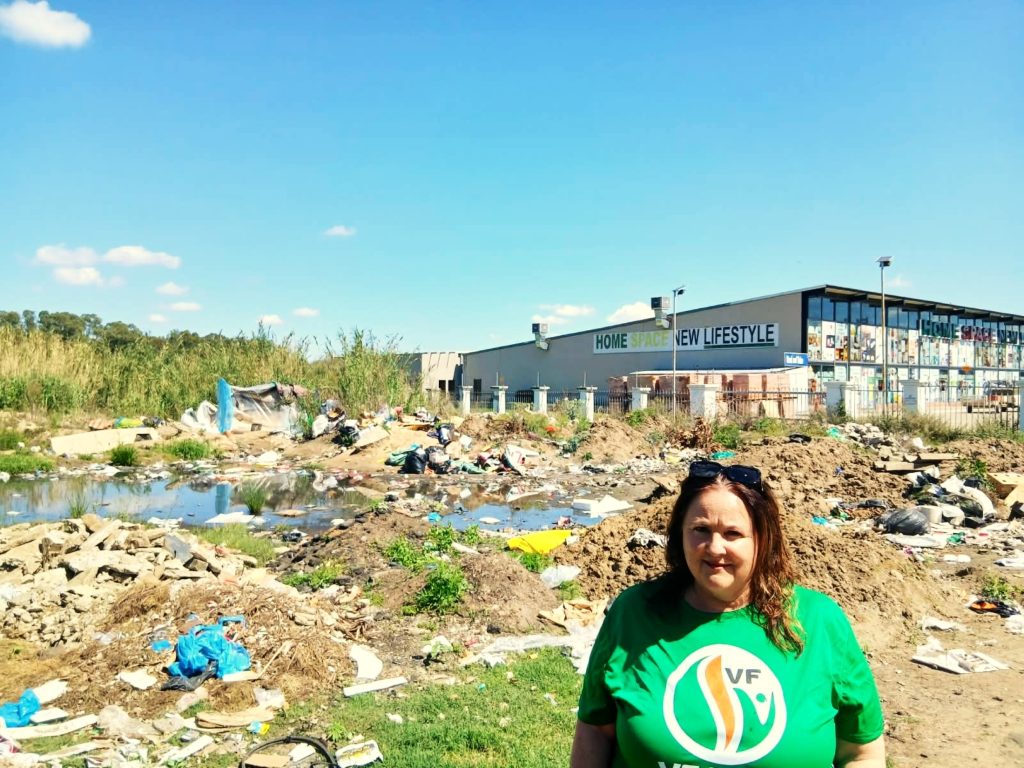 Lousanne van Heerden, VF Plus-raadslid van die Moqhaka munisipaliteit, staan by opgehoopte vullis in Kroonstad se middedorp, waar gebrekkige vullisverwydering tot ’n gesondheids- en veiligheidsrisiko vir inwoners lei. Foto: Verskaf