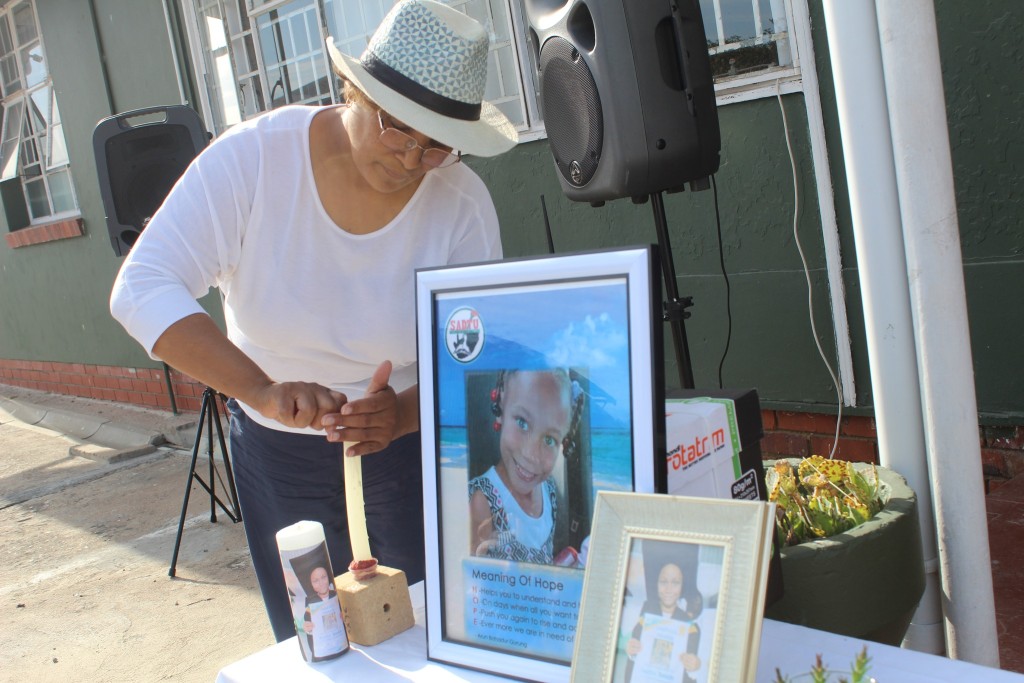 Edna Maart, Joshlin se onderwyser vir die enigste maand wat sy 'n graadeentjie kon wees, probeer 'n kers ter ere van Joshlin aansteek. Foto: Diazville Primêr