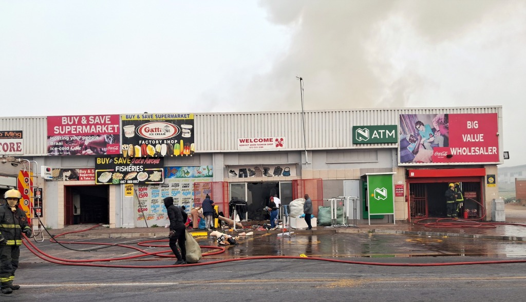'n Klerewinkel se goedere word uitgedra nadat ’n verwoestende brand. FOTO: Alida Buckle