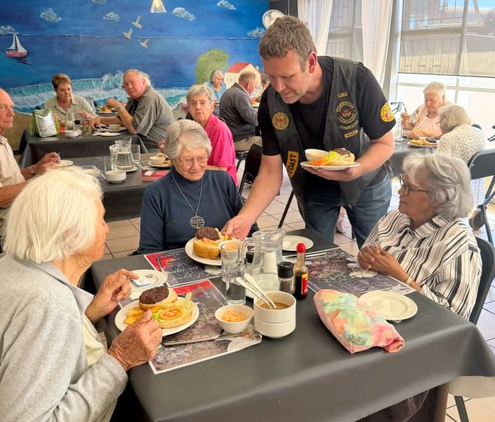 Benji Truter, kubpresident van Benji Truter, help om die hamburger-ete uit te deel.