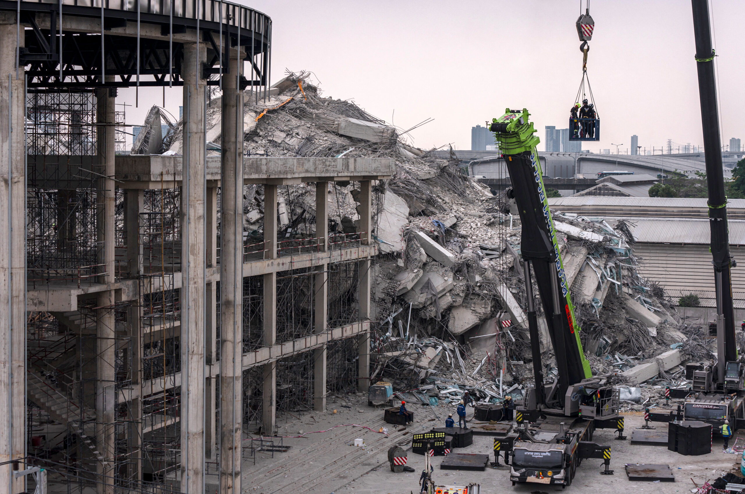 Rescue workers are lifted on a crane during search-and-rescue operations at the site of an under-construction building collapse in Bangkok on March 31, 2025, three days after an earthquake struck central Myanmar and Thailand. (Photo by Chanakarn Laosarakham / AFP)