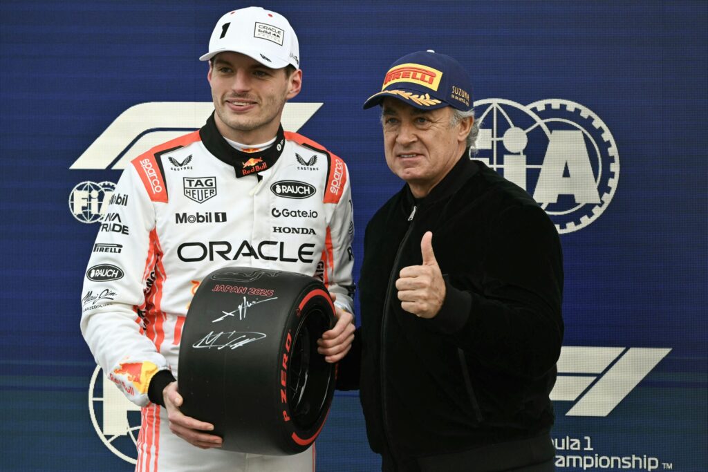Red Bull Racing's Dutch driver Max Verstappen (L), who took pole position, holds a tire that he signed as he poses for photos with French Former F1 driver Jean Alesi after the qualifying session of the Formula One Japanese Grand Prix.