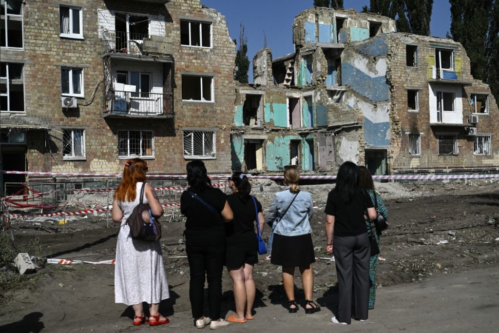Local residents stand in front of the residential building heavily damaged three days ago during a large-scale Russian drone and missile attack, in Kyiv on August 31, 2025, amid the Russian invasion of Ukraine. (Photo by Genya SAVILOV / AFP)