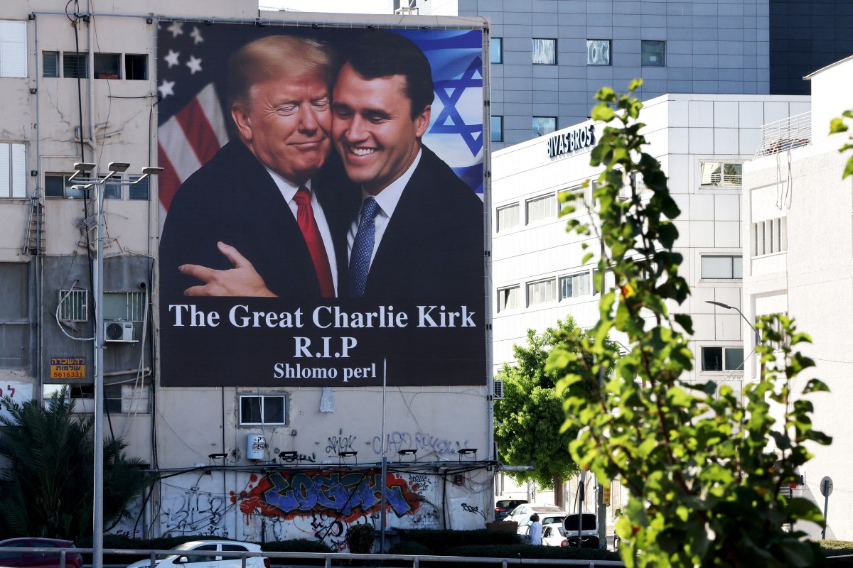 A billboard showing an image of US President Donald Trump (L) embracing US prominent right-wing activist Charlie Kirk, who was hit by a single bullet while addressing a large crowd at Utah Valley University in the town of Orem on September 10, hangs on the side of a building in Tel Aviv, on September 13, 2025. Trump on September 12, announced that the suspect had been taken into custody over the killing of right-wing activist Charlie Kirk after a massive manhunt. (Photo by Jack GUEZ / AFP)