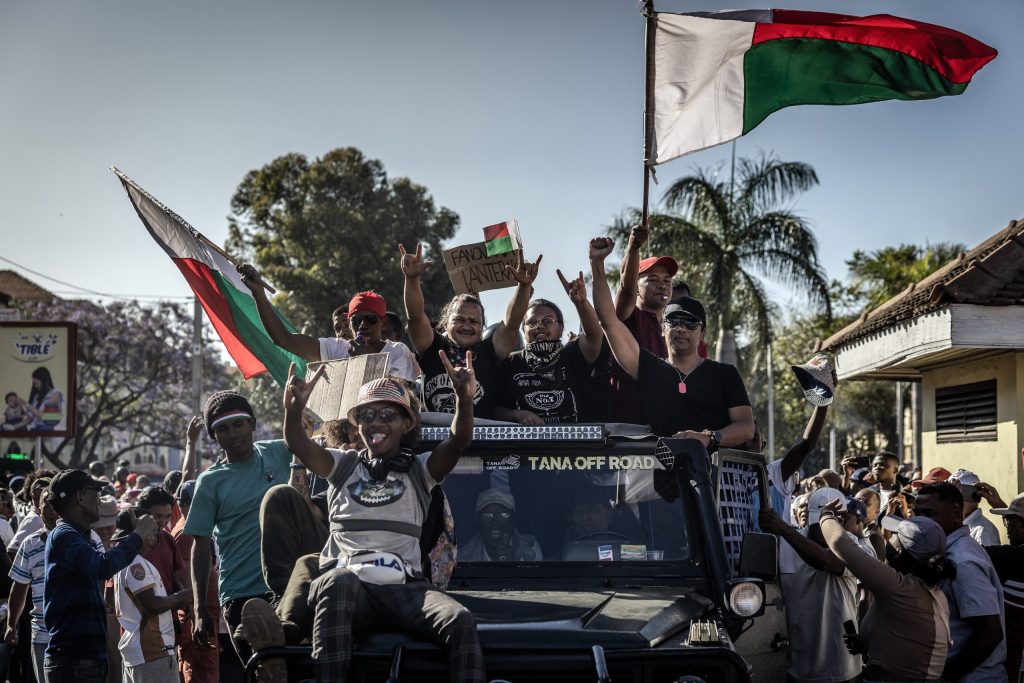 Residents ride in vehicles, waving Malagasy flags and chanting slogans, as a crowd follows members of Madagascar’s Army CAPSAT unit moving toward the Presidential Palace to gain entry in Antananarivo, October 14, 2025.
An elite Madagascar military unit told AFP on October 14, 2025 it had taken power in the country after the national assembly voted to impeach President Andry Rajoelina for desertion of duty.