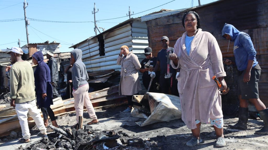 Woman stands where home was destroyed by fire in Ethembeni settlement.