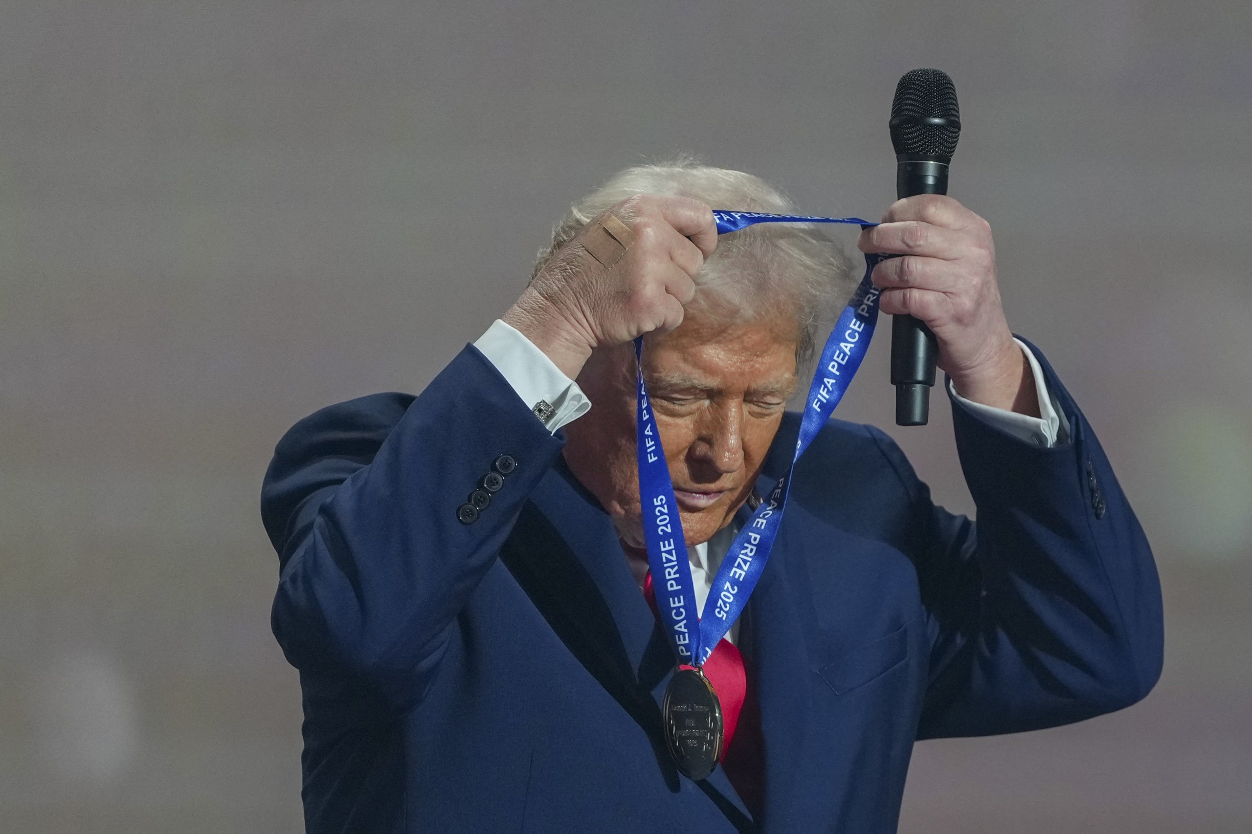 US President Donald Trump puts on his FIFA Peace Prize medal.