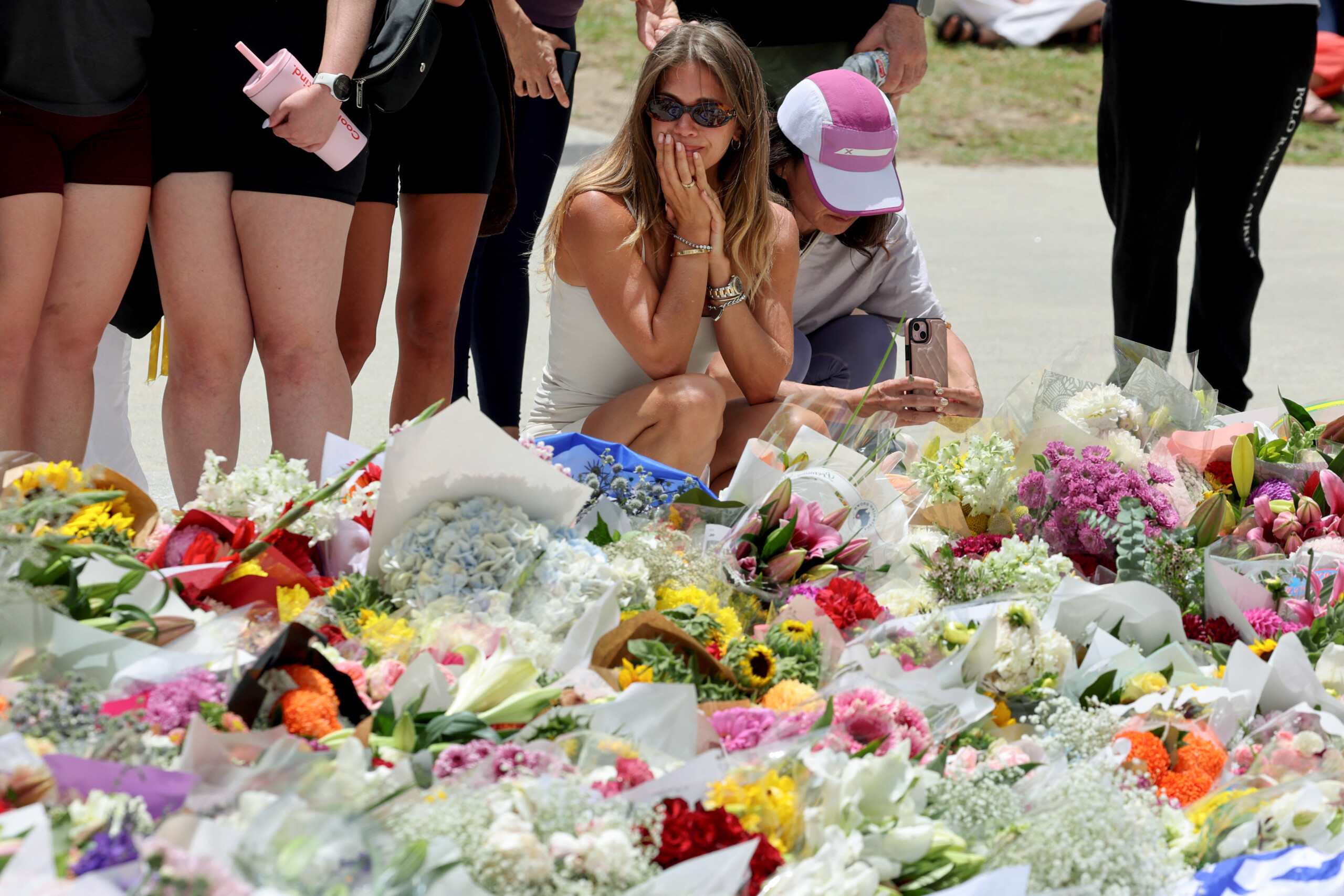 Mourners gather by floral tributes at the Bondi Pavillion in memory of the victims of a shooting at Bondi Beach, in Sydney on December 15, 2025. A father-and-son team toting long-barrelled guns shot and killed 15 people including a 10-year-old girl at Sydney's Bondi Beach on December 14, with authorities labelling it an antisemitic terrorist attack on a Jewish festival.