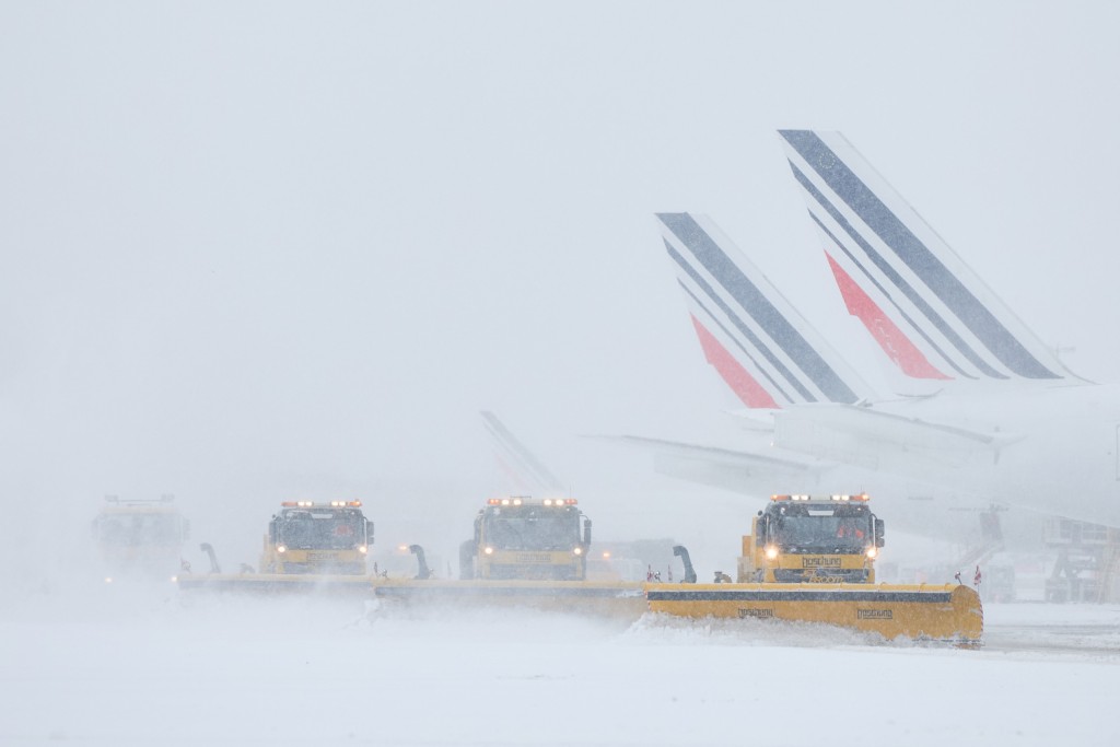 Air France airplanes are seen on the tarmac as snowplows clear the runways.
