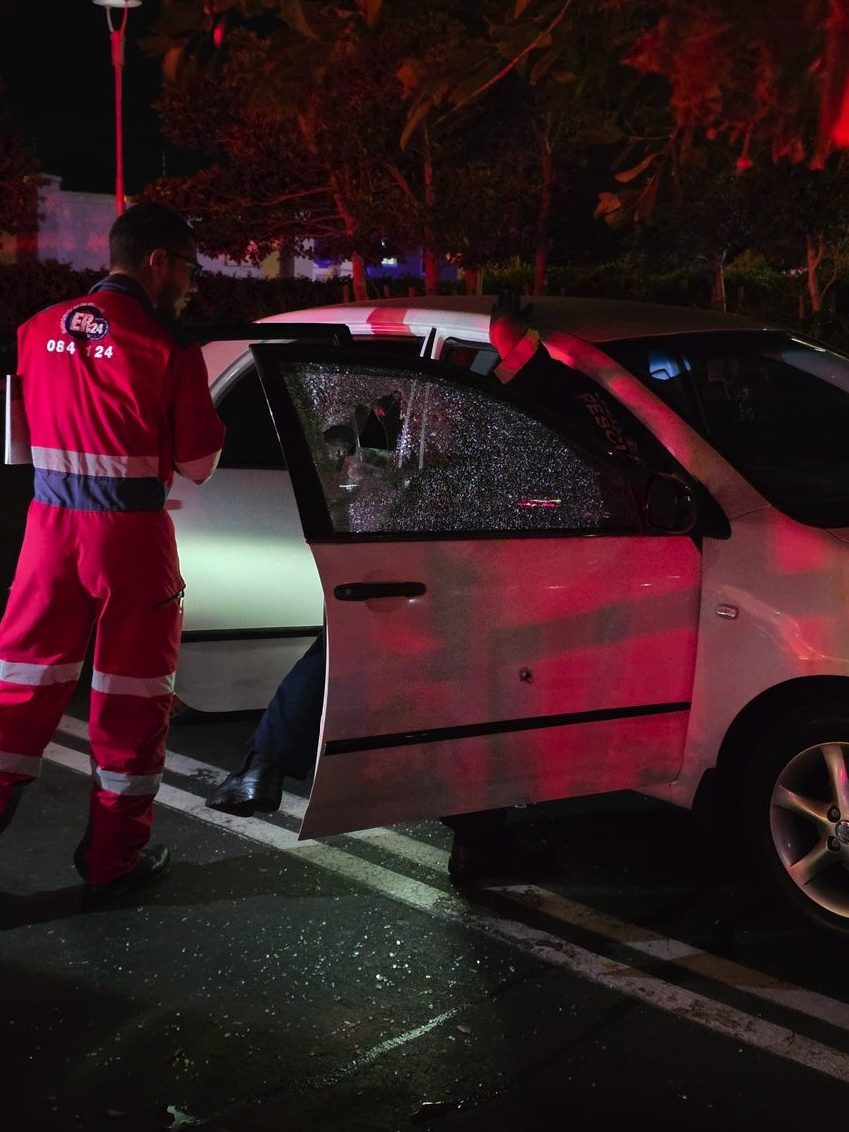 Emergency services examining bullet-damaged Toyota Corolla at Gordon's Bay Mall shooting scene