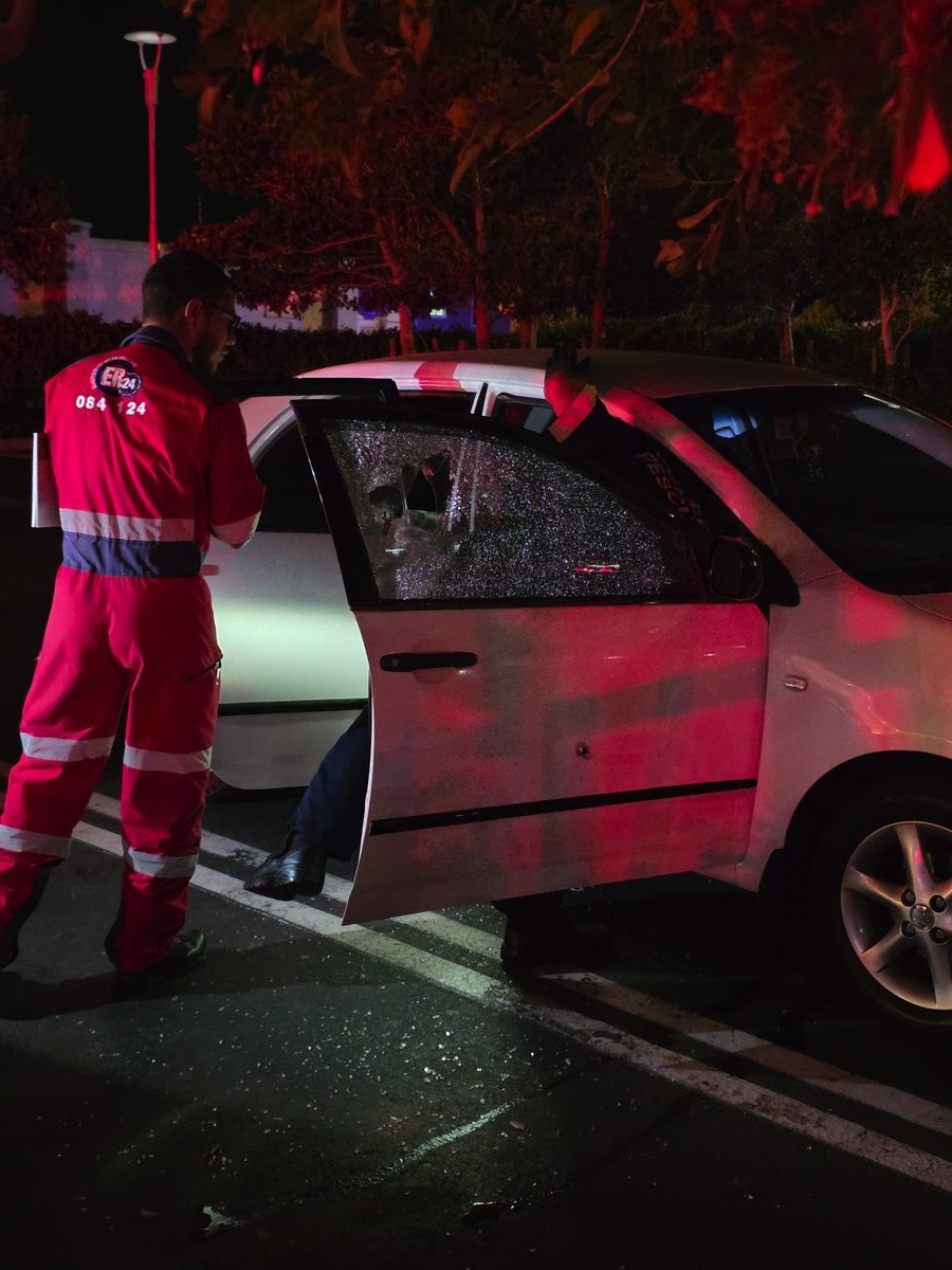 Emergency services examining bullet-damaged Toyota Corolla at Gordon's Bay Mall shooting scene