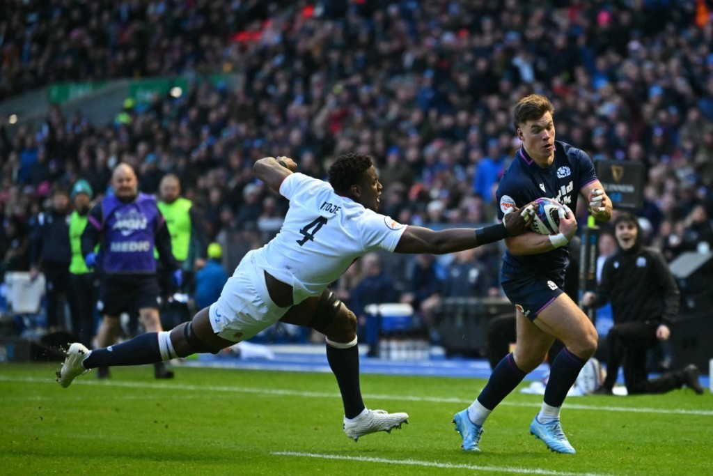 Scotland's centre Huw Jones (R) runs away from England's lock Maro Itoje (L) to score their first try during the Six Nations international rugby union match between Scotland and England at Murrayfield Stadium in Edinburgh, Scotland on February 14, 2026. 
