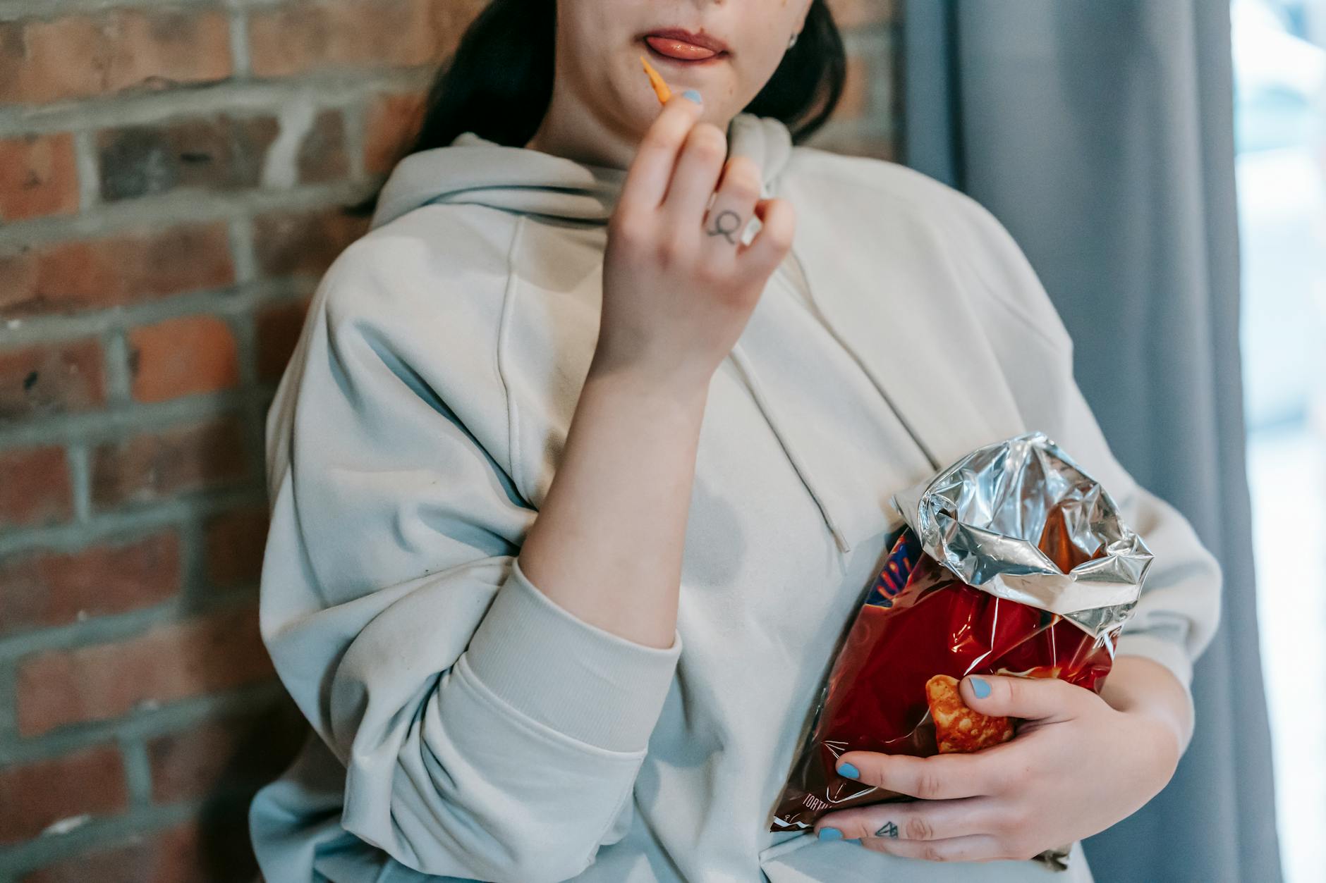 crop woman eating savory snacks