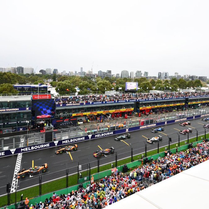 Formula 1 racing car speeding along track at Melbourne Grand Prix with sponsor signage.