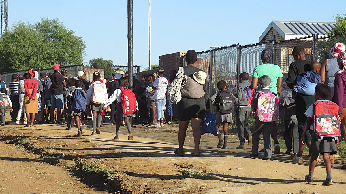 Parents and children attending the Matla Primary School in Phase 6, at the gate of the school. PHOTO: Teboho Setena