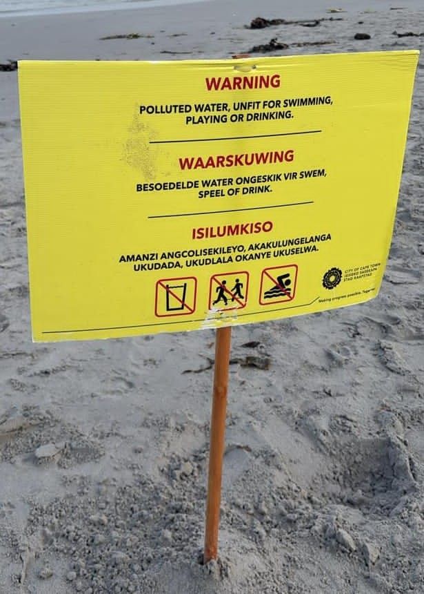 Signage at Melkbosstrand Beach warns beachgoers of the polluted water.
