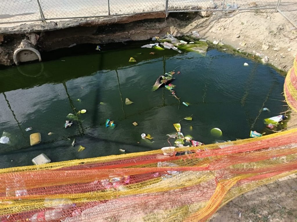 Konstruksieholte met groen water en rommel wat tydens bouwerk versamel het