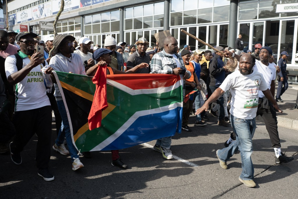Demonstrators hold a South African flag as they march during a protest against undocumented migrants.