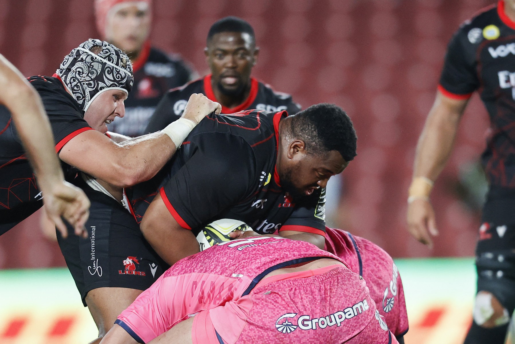 Lions' prop Asenathi Ntlabakanye is tackled by Stade Francais' prop Giorgi Melikidze (C-R) during the European Challenge Cup