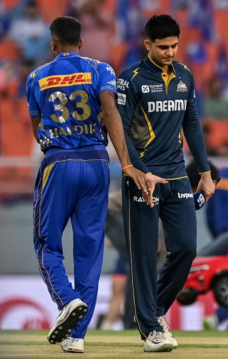 Mumbai Indians' captain Hardik Pandya (L) and his Gujarat Titans' counterpart Shubman Gill leave after the toss before the start of the Indian Premier League (IPL) Twenty20 Eliminator