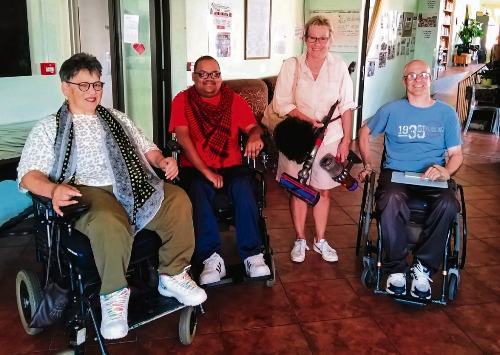 Residents Rosabelle Riese, Allen Petersen (head: book project) and Terence Moore are with Gillian Watson, a volunteer.