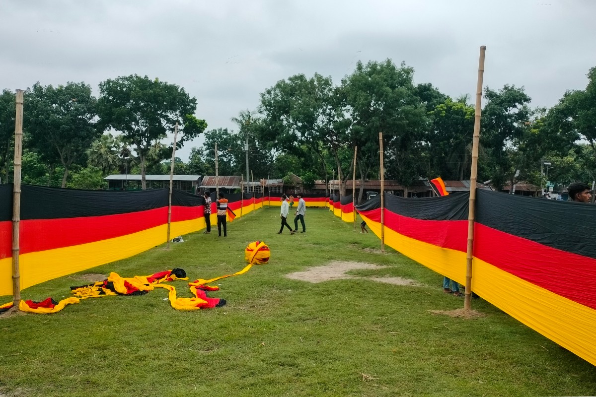 People look at a 7,5 km long national flag of Germany commisioned by their football team fan Bangladeshi farmer Amjad Hossain, upon its display across a field in Magura district.