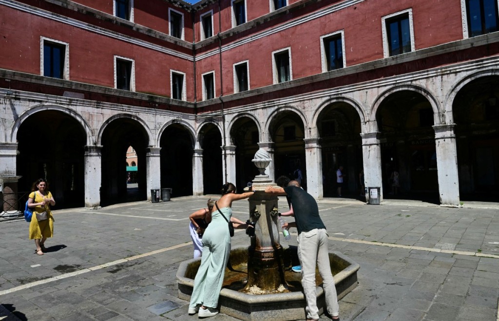 People fill bottles from a public water fountain during a heatwave in Venice on June 27. Photo: Stefano Rellandini | AFP