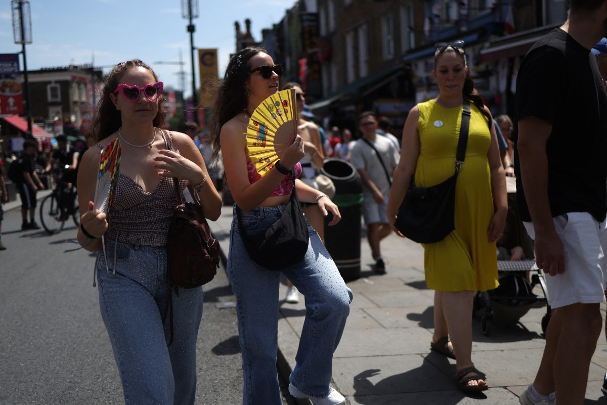 Shoppers use fans while visiting Camden in central London on June 27, 2026, during a heatwave. Photo: Toby Shepheard | AFP
