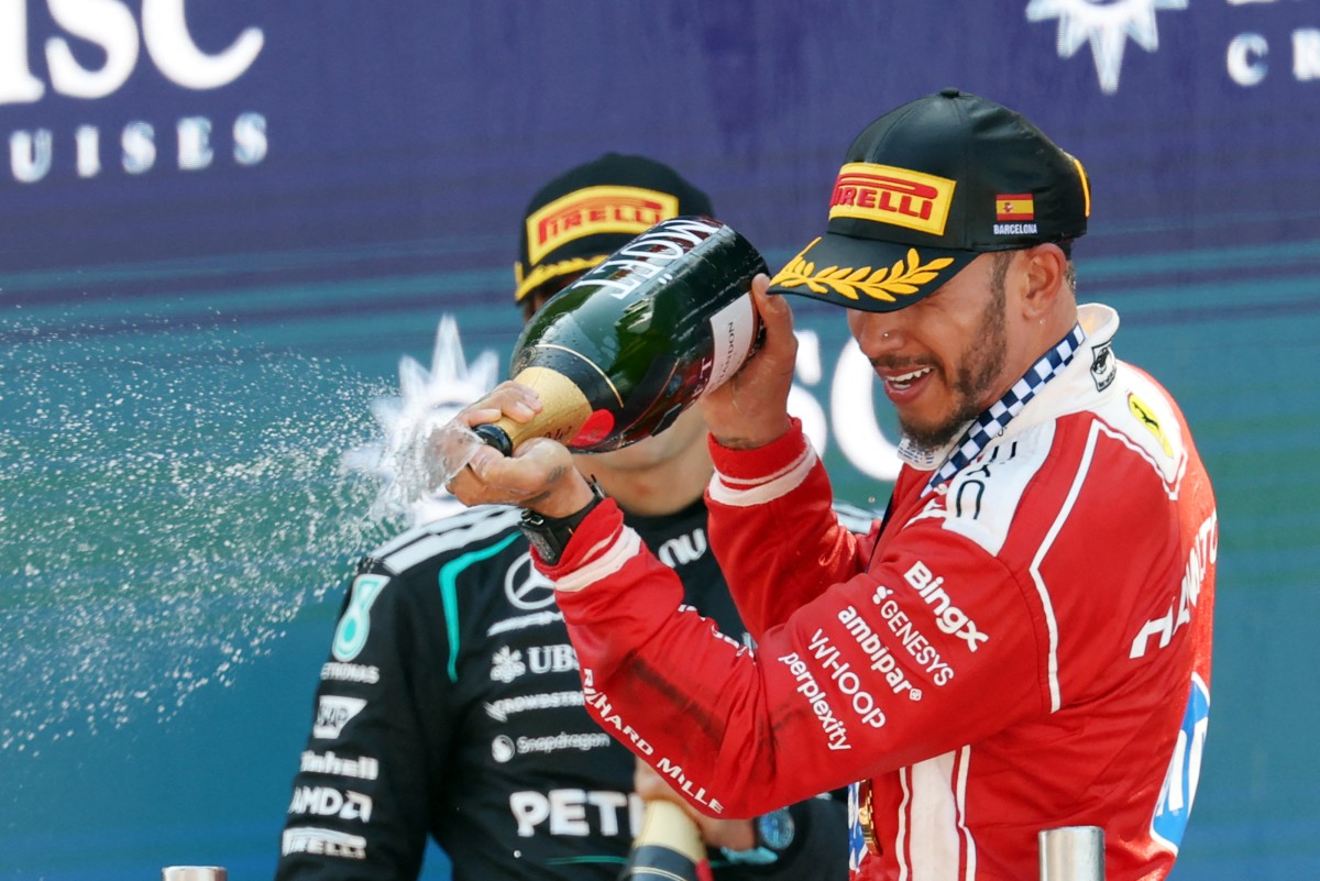 Winner Ferrari's British driver Lewis Hamilton (R) and second placed Mercedes' British driver George Russell celebrate in the podium after the Catalonia Formula One Grand Prix
