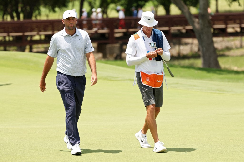 Scottie Scheffler of the United States and caddie Ted Scott walk off the first green during the final round.