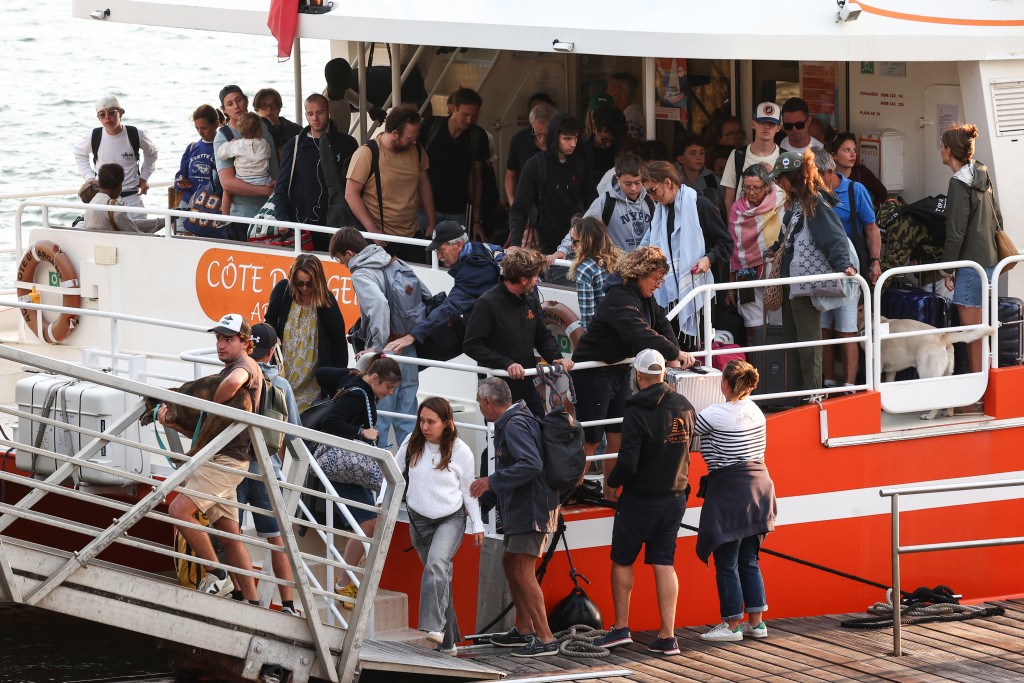 Holidaymakers from Lege-Cap-Ferret disembark from a boat upon their arrival in Arcachon during an evacuation operation of the entire Cap-Ferret peninsula, in southwestern France, on July 24, 2026 whilst a wildfire is spreading across the area. (Romain Perrocheau/AFP