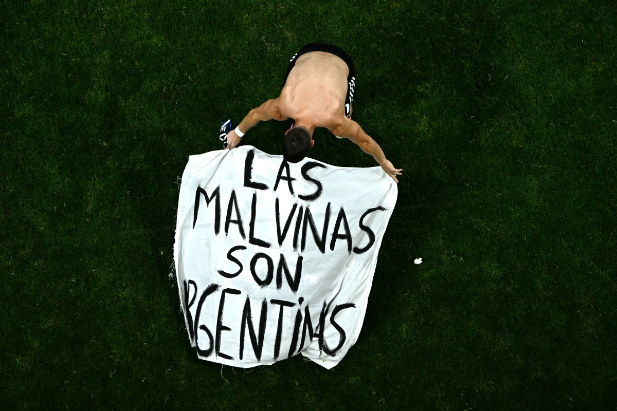 Argentina's midfielder Giovani Lo Celso adjusts a banner reading "The Malvinas (Falkland Islands) belong to Argentina"