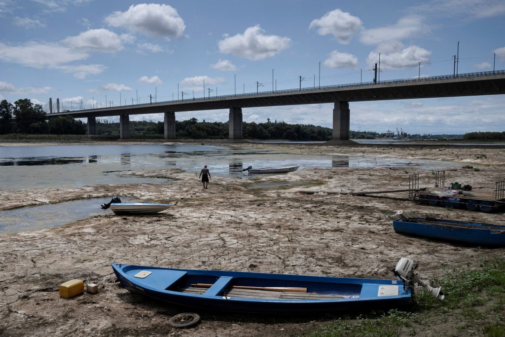 A fisherman tries to move his boat, blocked by algae on the bottom of the Danube river.