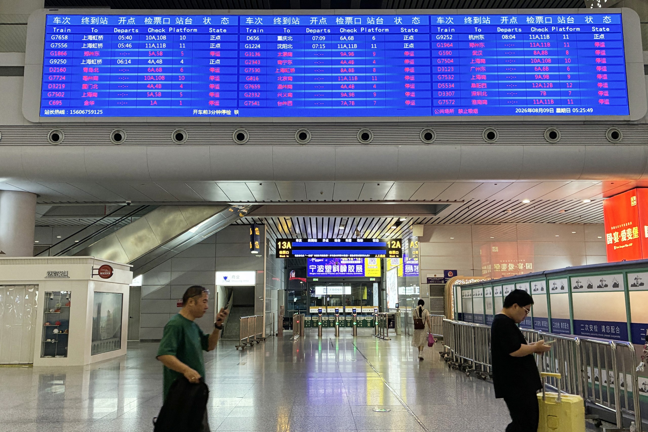 assengers walk under a departure board at Ningbo railway station as most trains are cancelled due to approaching Typhoon Dolphin on August 9, 2026. (Photo by Rebecca BAILEY / AFP)