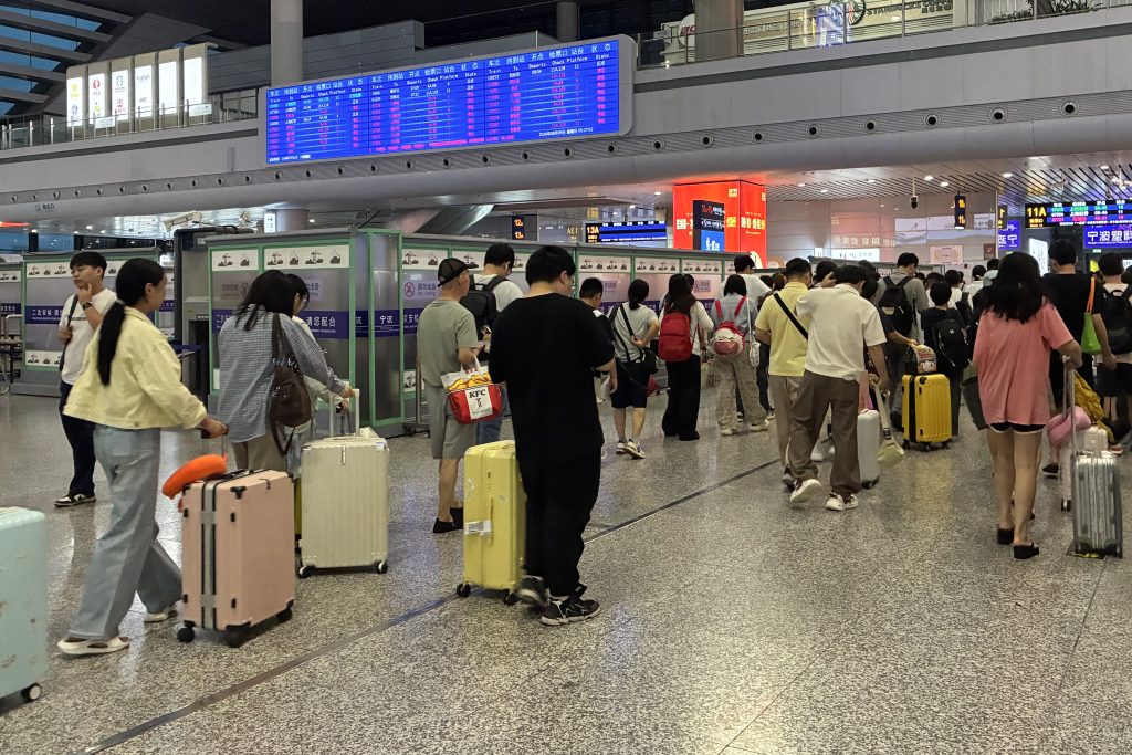Passengers walk under a departure board at Ningbo railway station