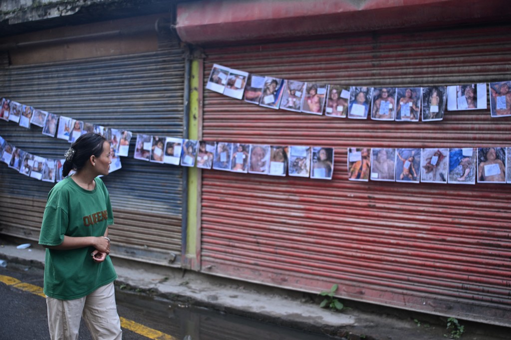 A woman looks at photographs of the missing and dead outside a hospital in Kathmandu. Photo: Prakash Mathema/AFP