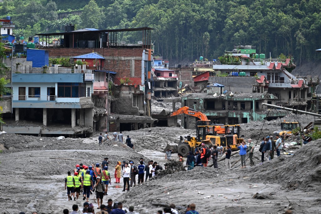 Workers use excavators to clear mud at Dhunge Bazaar in Nuwakot district. Photo: Arun Sankar/AFP