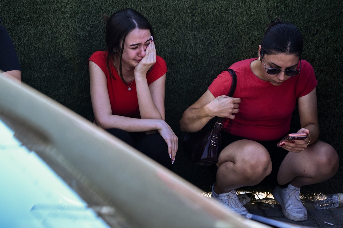People react as they await news of their loved ones outside the port in Kyrenia