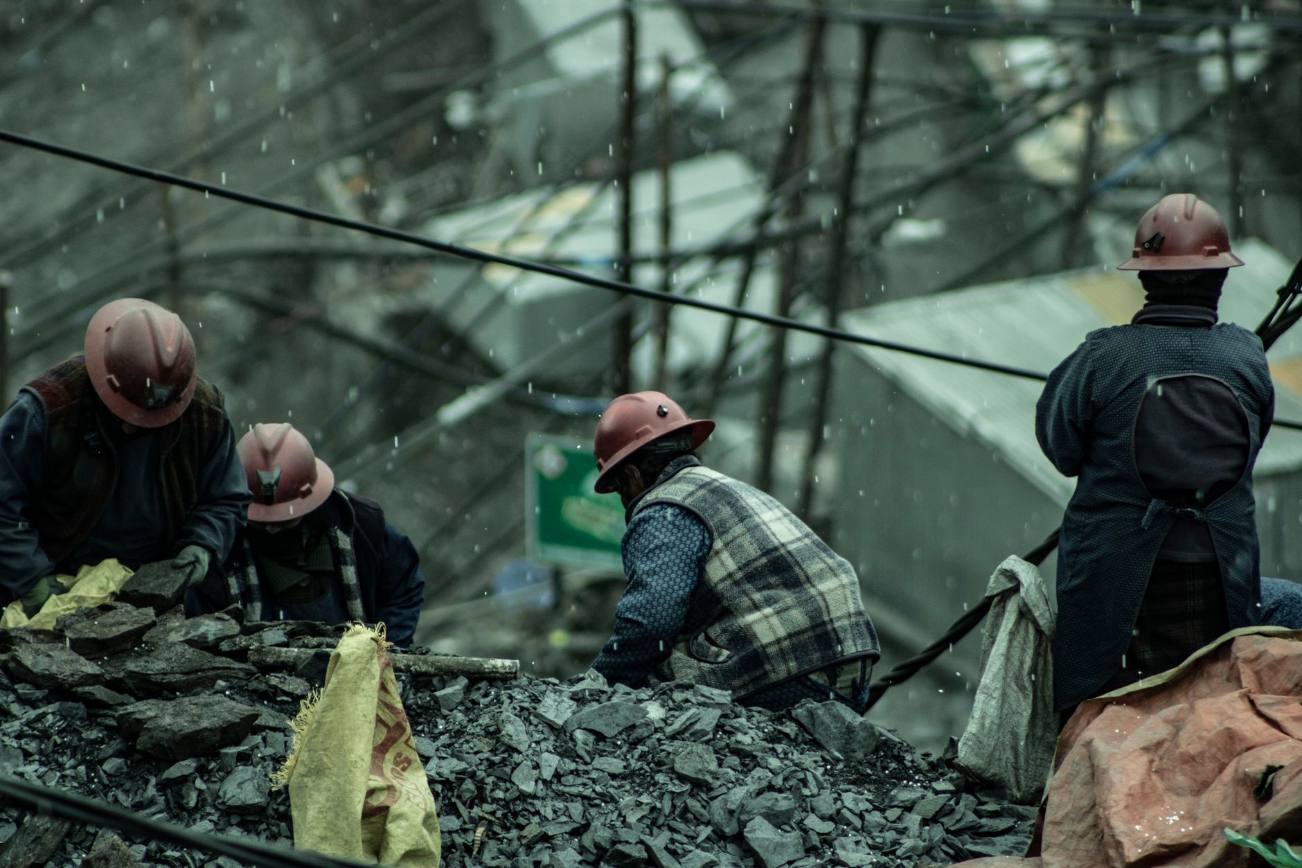 group of people searching gold in a pile of mine waste during the rain