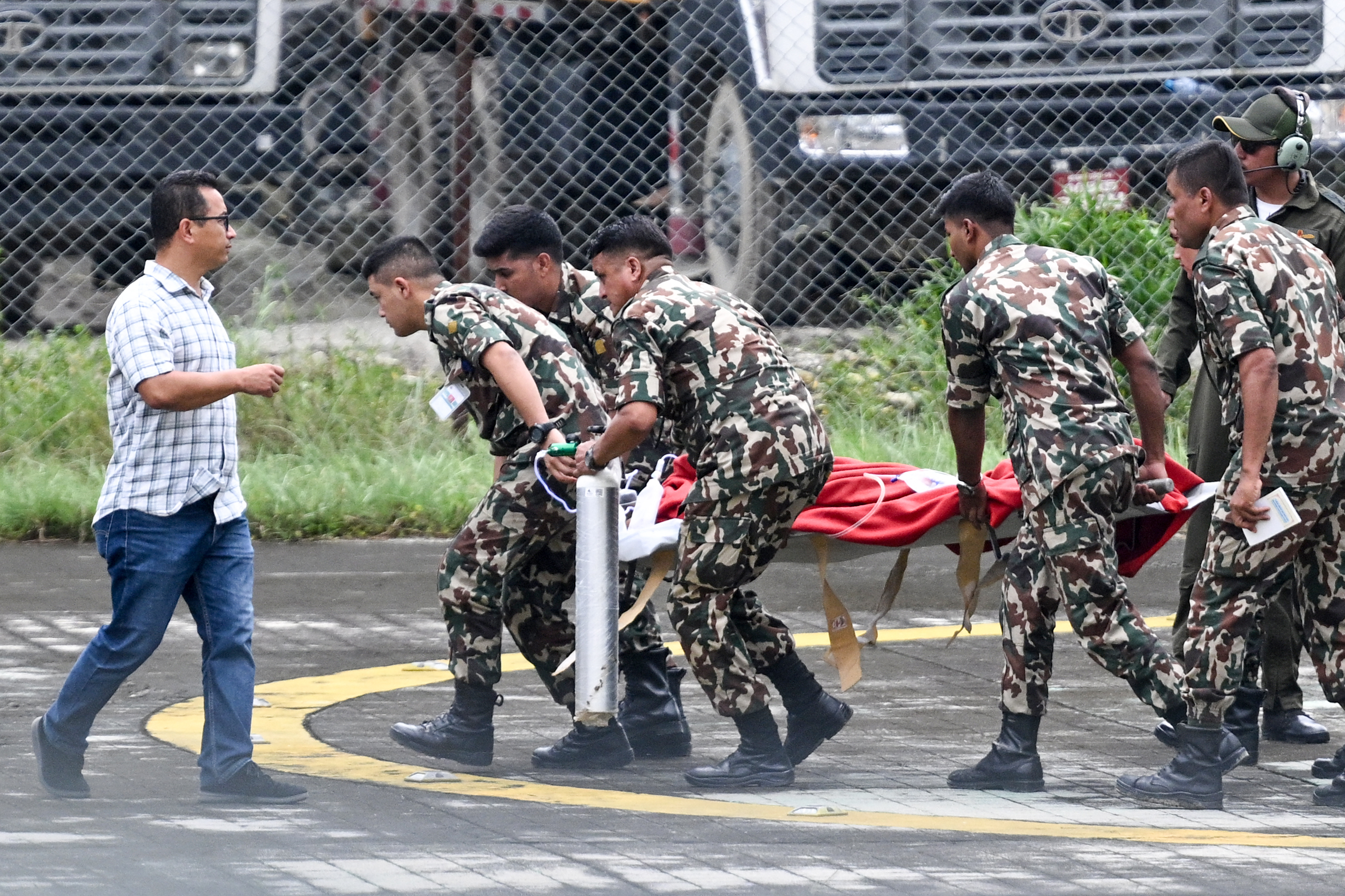 Army personnel disembark a helicopter carrying Kabir Maharjan, a worker who was trapped inside a tunnel of Trishuli-3A Hydropower Project,