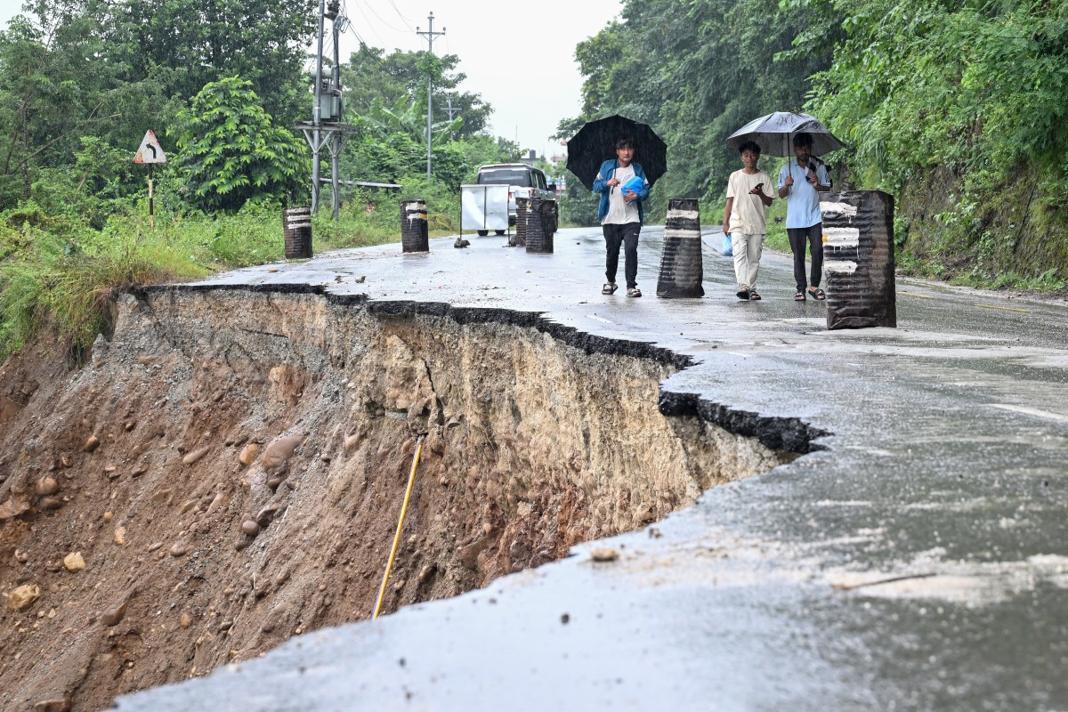 People walk along a washed-out highway in the aftermath of the August 26 flash flood in Nepal.