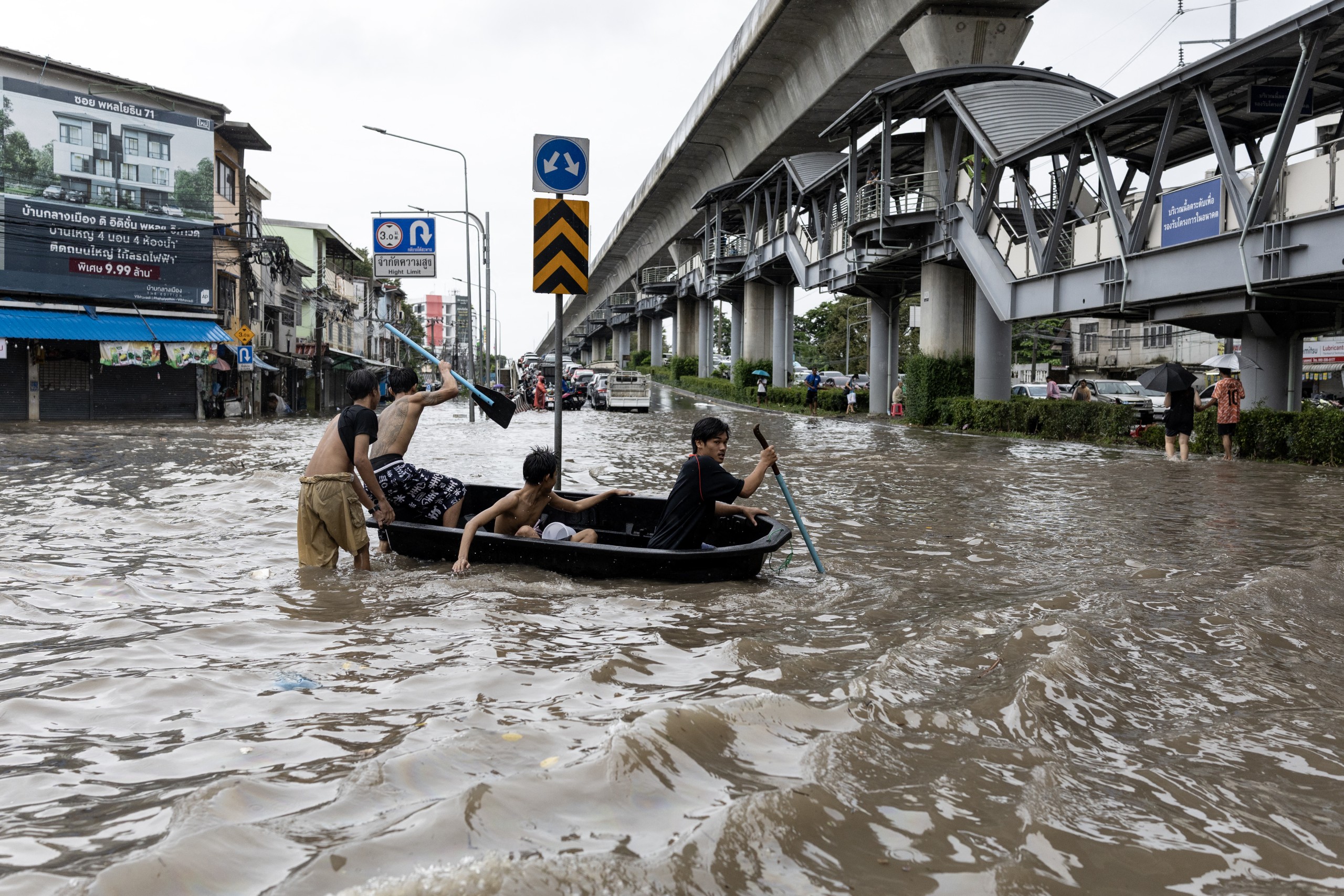 Young men navigate a small boat through floodwaters in the Bang Bua district of Bangkok on Saturday 26 September. Photo: Wikus de Wet/AFP