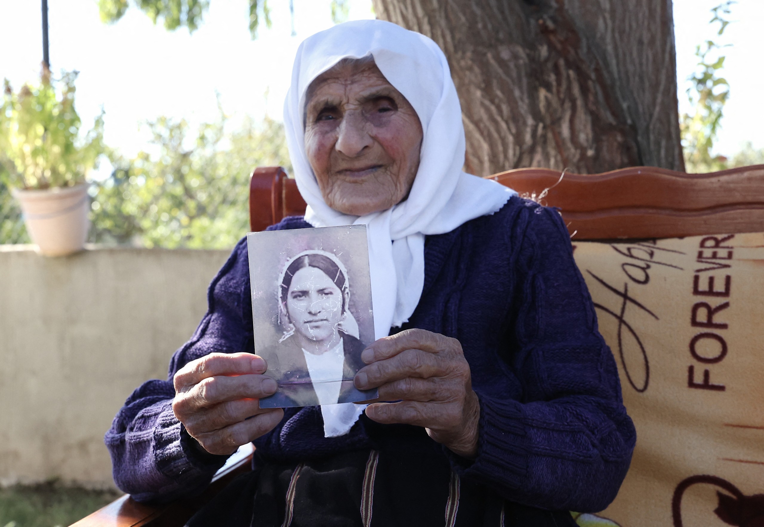 The 117-year-old Qamile Marra holds a black and white photograph from her youth.