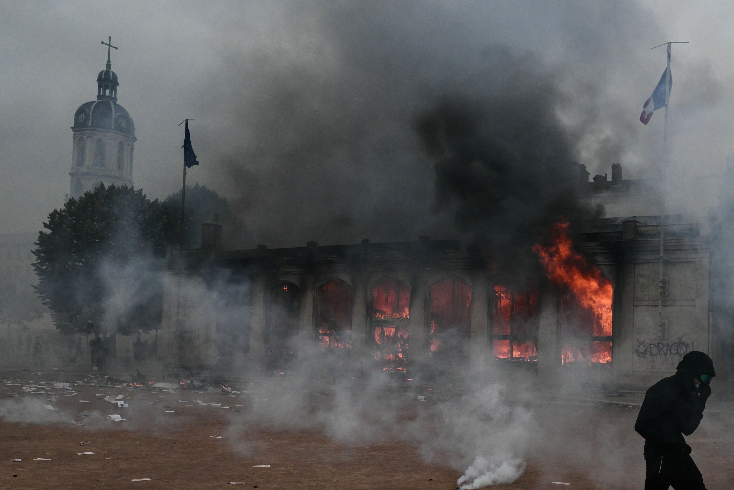 A protester reacts as he walks among tear gas in front of Lyon's tourism office during a demonstration to protest against the "high cost of living", in Lyon, southeastern France, on October 17, 2026 as part of a nationwide call for mobilisation bringing together various groups expressing their anger: former "Yellow Vests", secondary school and university students, climate activists and even farmers. After weeks of student protests, France faces broader, nationwide demonstrations on October 17, 2026 over the cost of living, setting up a potentially fraught six months heading into a presidential election. A police source told AFP that authorities estimated nearly 200,000 people could take part, with 40,000 in Paris. Photo: Jeff Pacoud | AFP