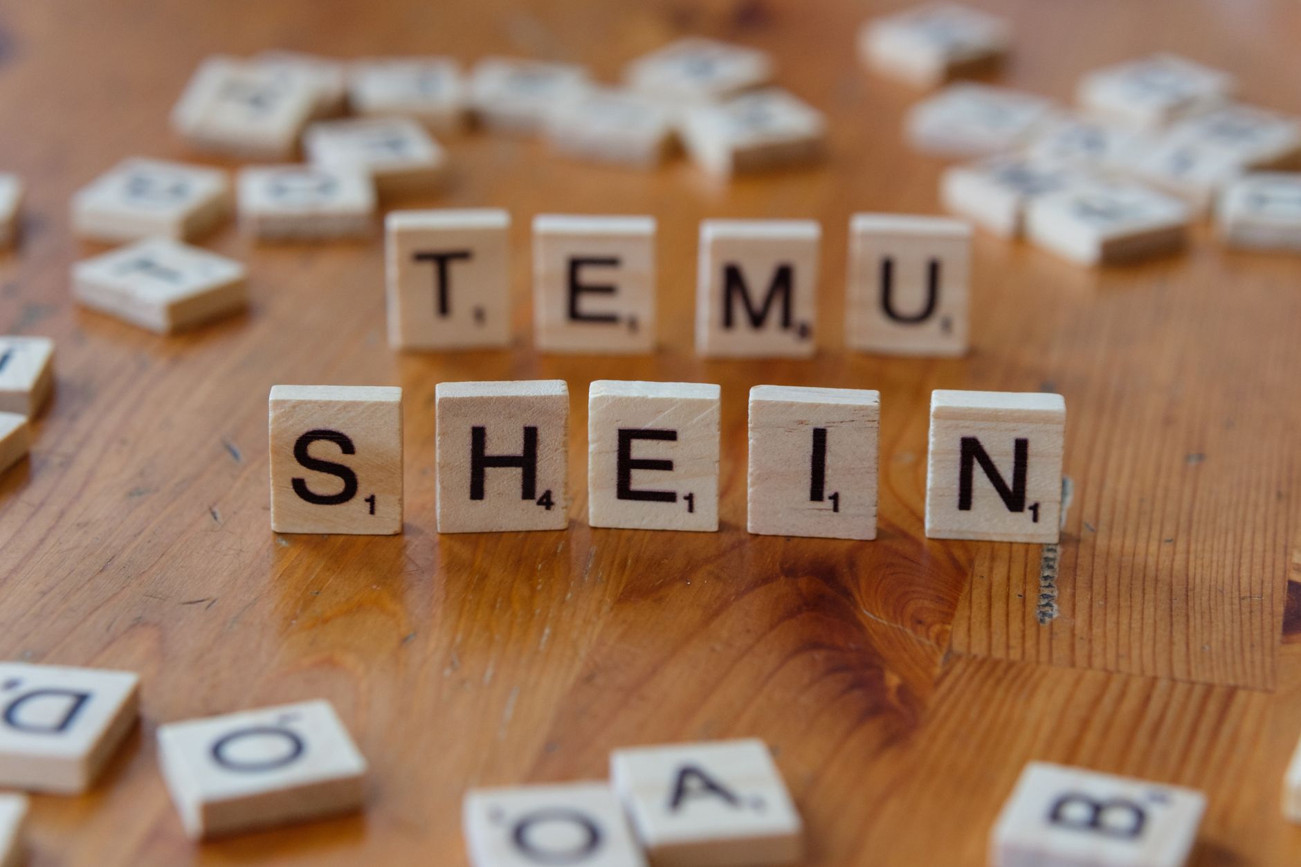 scrabble tiles spelling temu shein on wooden table